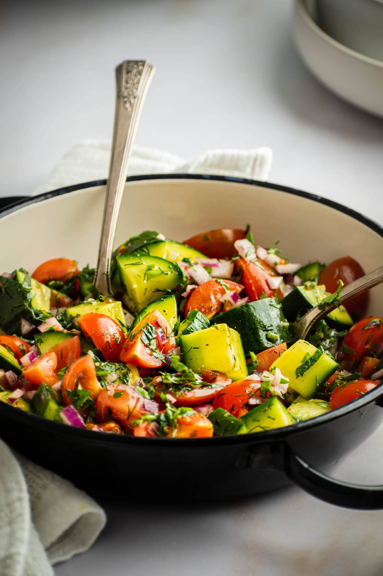 Tomato and cucumber Israeli salad with fresh herbs in a bowl with lemon juice and olive oil.