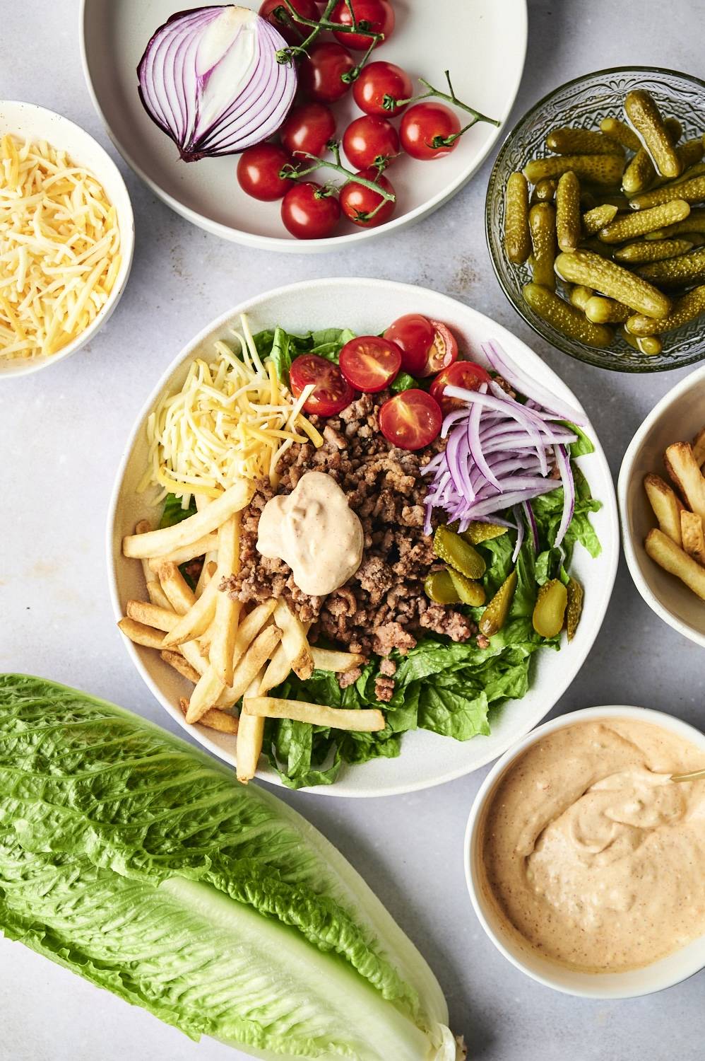 Healthy burger bowls with ground beef, special sauce, french fries, lettuce, tomatoes, and pickles.