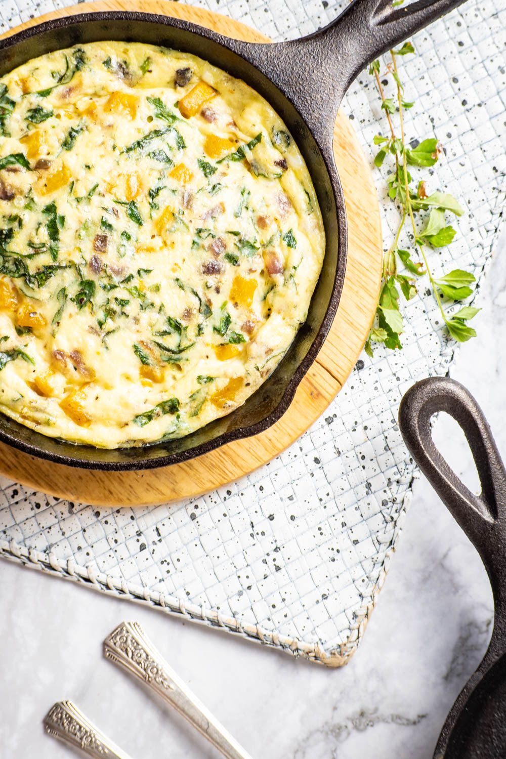 Butternut Squash and Spinach Egg Casserole in a pan with a cutting board underneath.