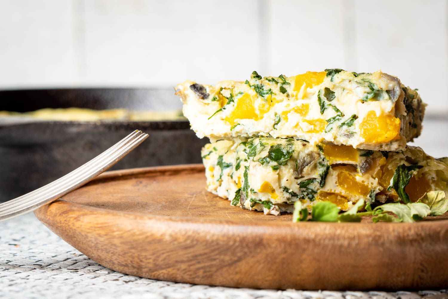 Side view of butternut squash and spinach egg casserole with blurred background.