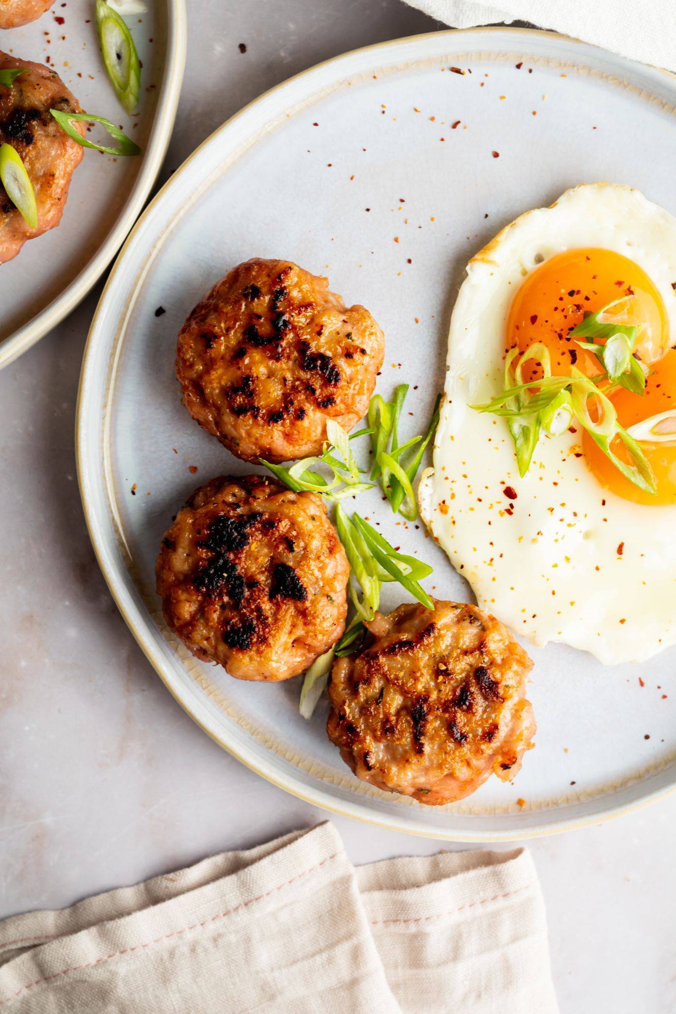 Chicken sausage breakfast patties served with a sunny side up egg and green onions.