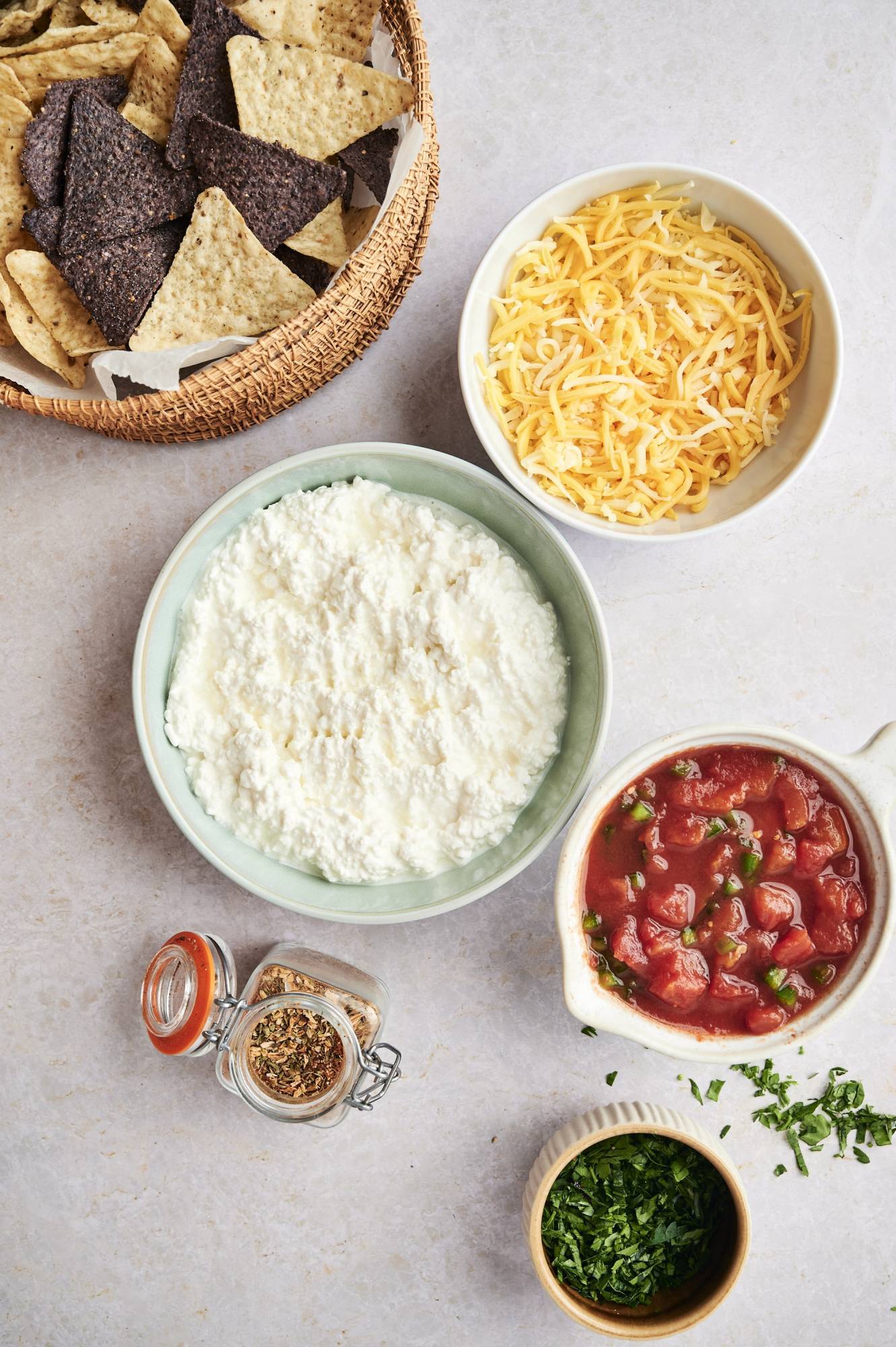 Ingredients for cottage cheese queso including cottage cheese, shredded cheddar cheese, tomatoes, green chilies, and taco seasoning.