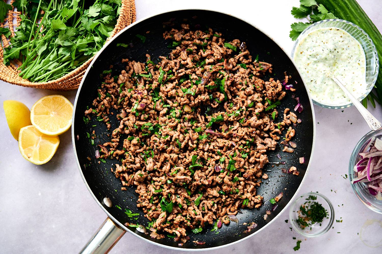 Kofta ground beef in a skillet with red onion, parsley, and spices.