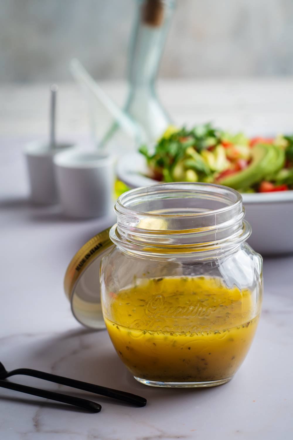 Healthy Italian dressing with olive oil and red wine vinegar in a jar with a green salad.