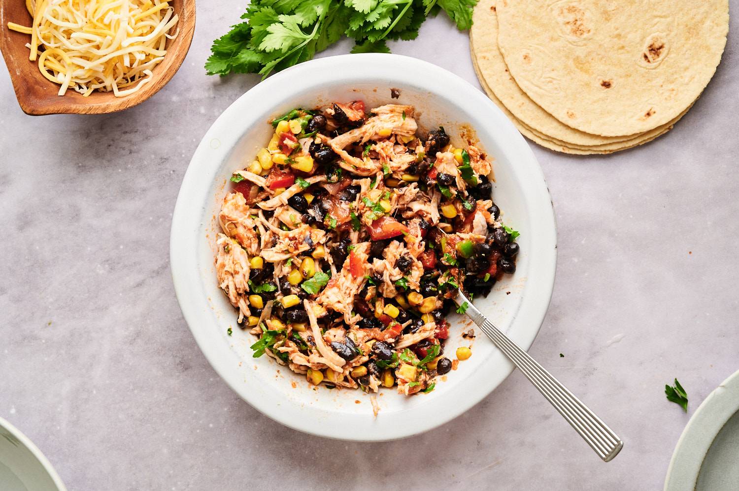 Spicy shredded chicken, black beans, tomatoes, corn, and tomatoes in a bowl for quesadillas.