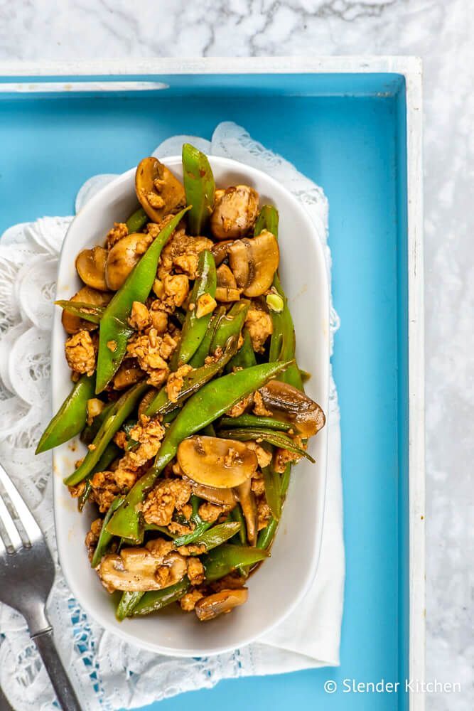 Turkey stirfry with mushrooms and green beans on a blue plate with chopsticks.