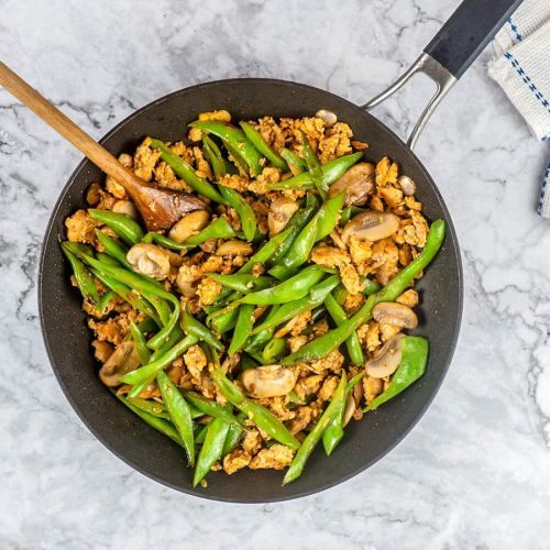 Ground Turkey stir fry with green beans and mushrooms in a black skillet with a wooden spoon.