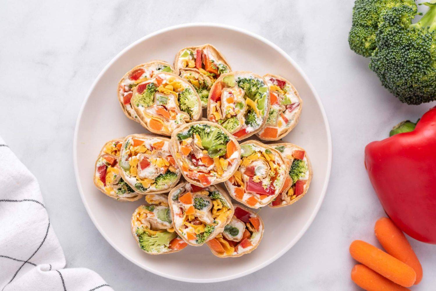 Healthy cream cheese pinwheels with vegetables served on a white plate/