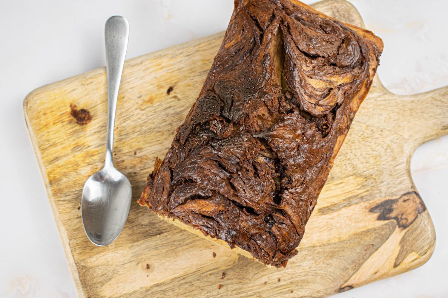 Nutella banana bread with swirls of nutella and banana on a wooden cutting board.