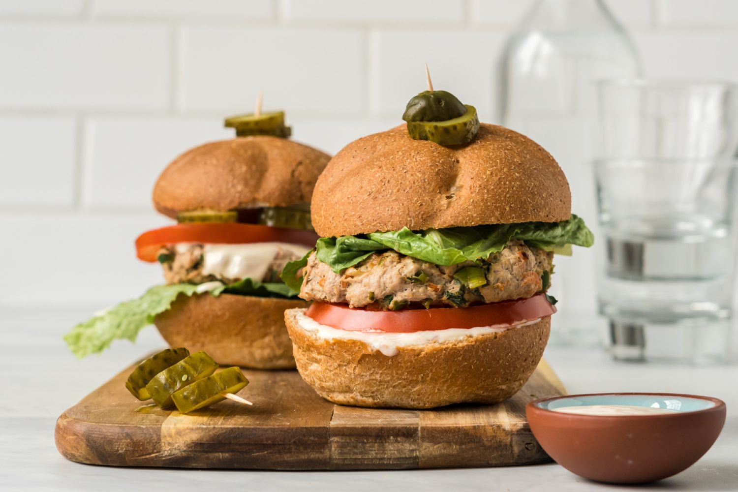 Asian turkey burgers with lettuce, tomato, and sweet chili yogurt sauce on two buns,
