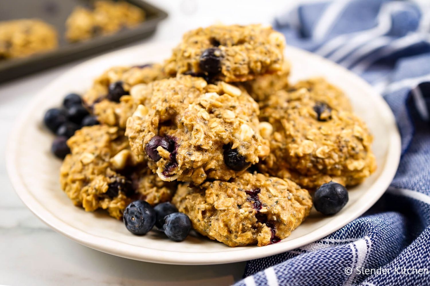 Blueberry breakfast cookies with rolled oats, bananas, fresh blueberries, chocolate chips, and chia seeds on a plate.