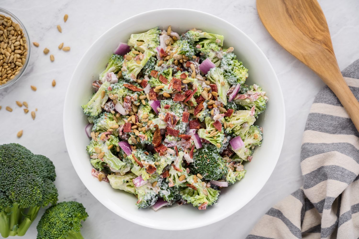 Fresh broccoli salad made with fresh broccoli florets, red onion, raisins, sunflower seeds, and bacon in a creamy yogurt dressing.