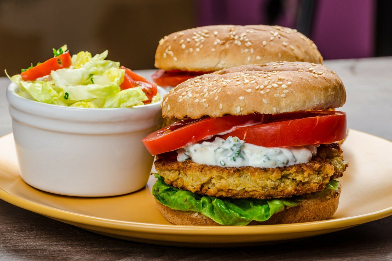 Chickpea burgers made with feta cheese topped with yogurt sauce, lettuce, and tomatoes.
