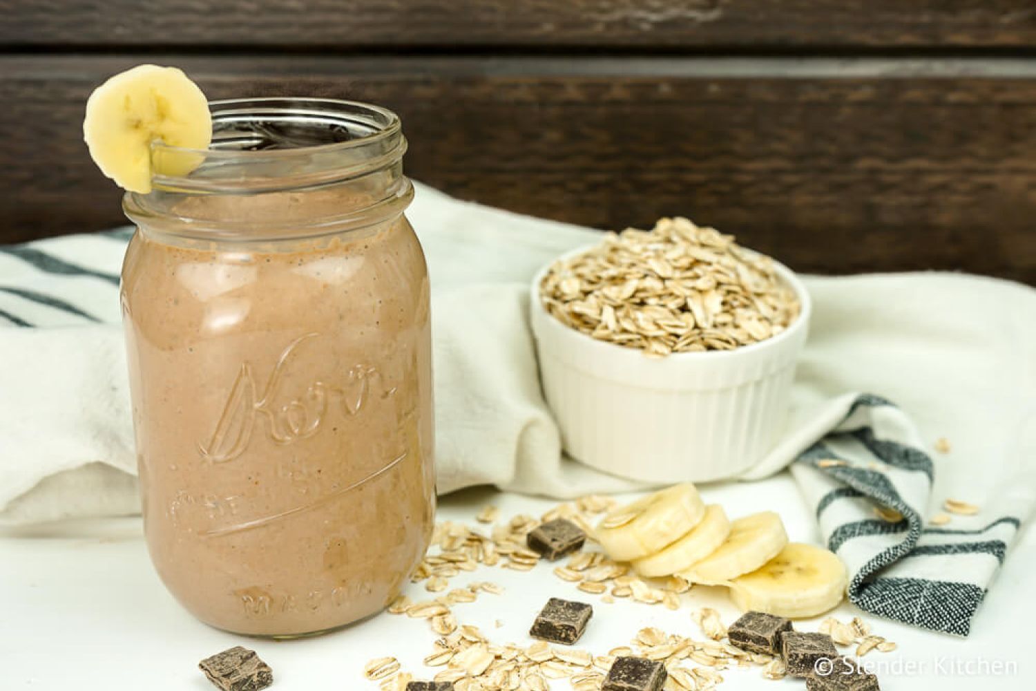 Chocolate banana smoothie in a mason jar with banana and chocolate chips on the side.