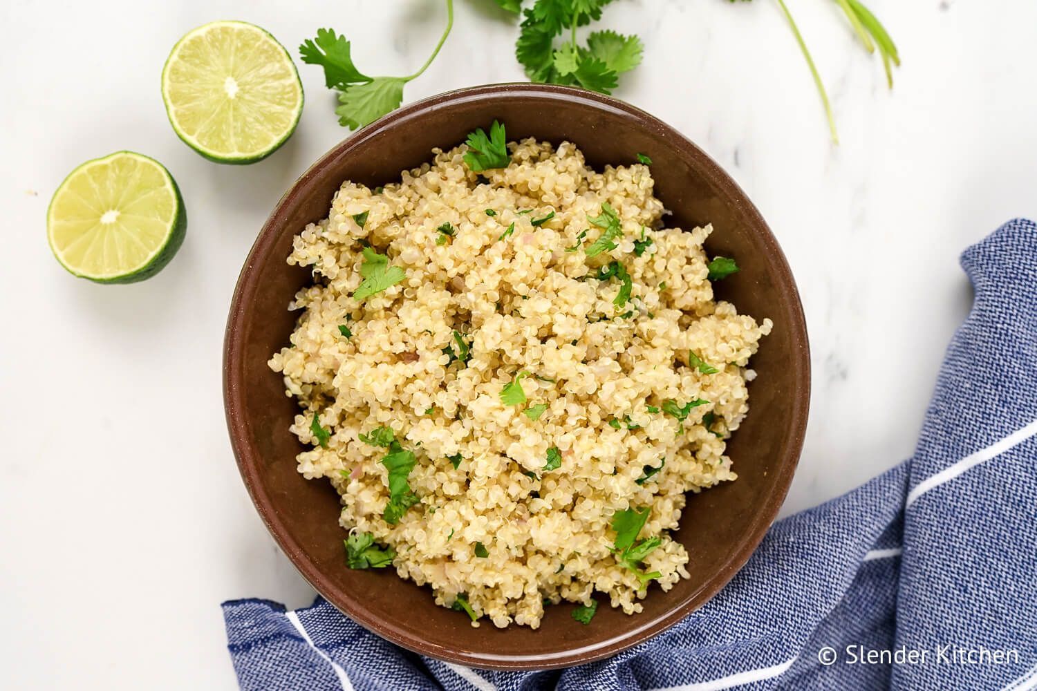 Cilantro lime quinoa in a bowl with cilantro leaves, lime zest, garlic, and onion.