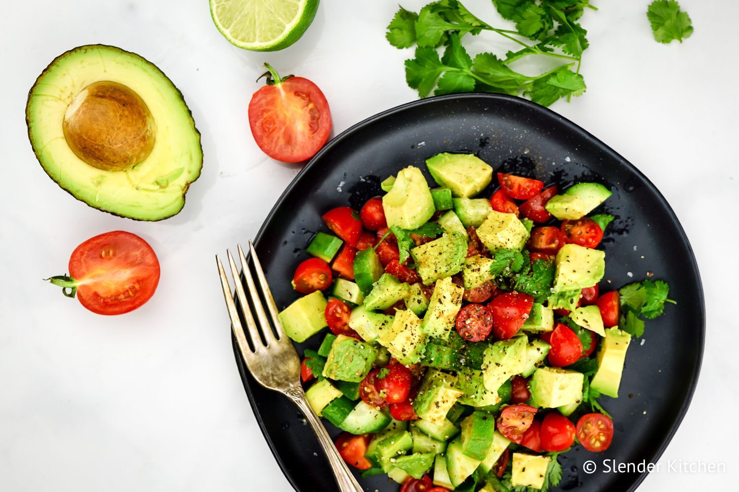 Cucumber avocado salad with tomatoes in a wooden bowl.