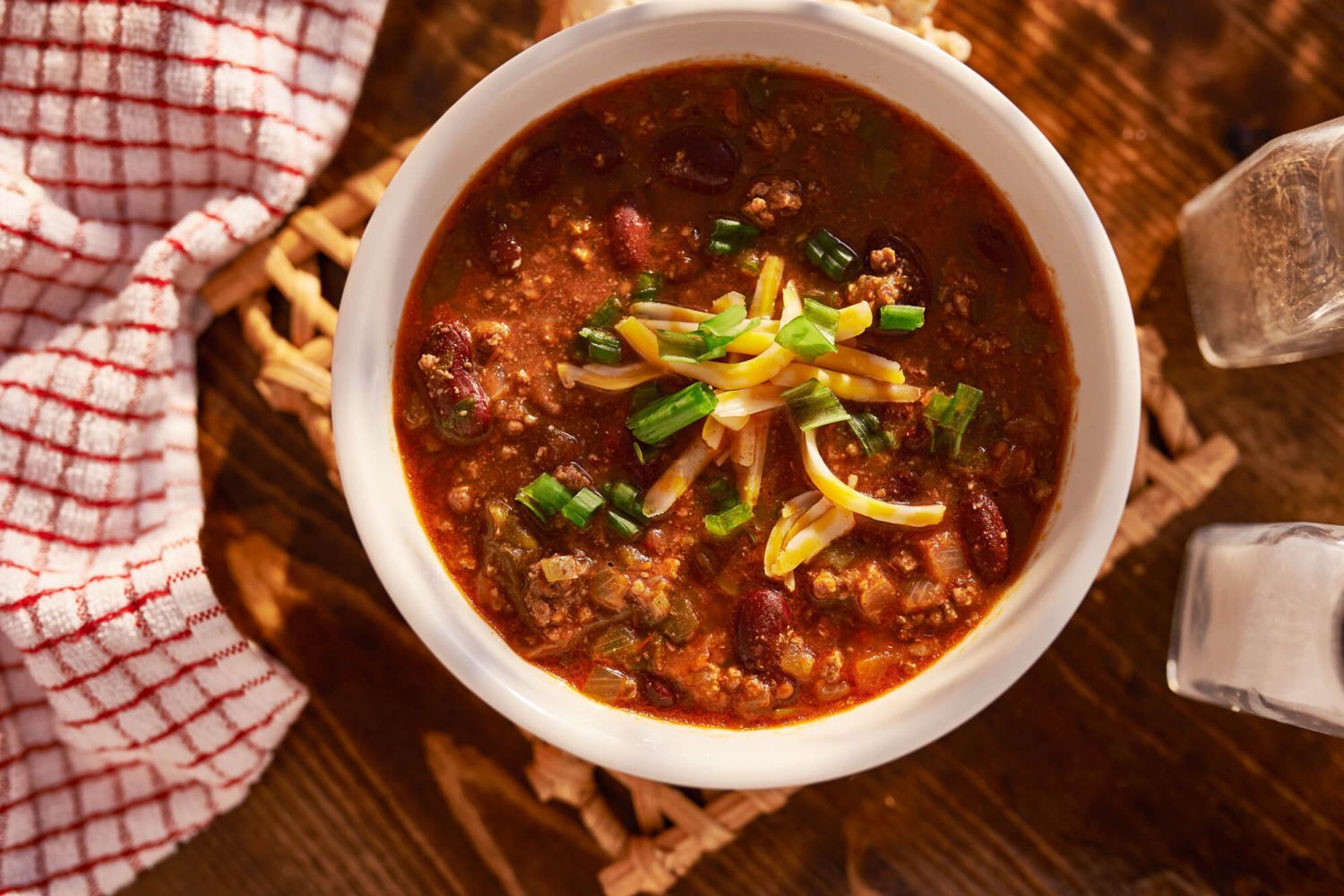 Easy beef chili in a bowl with shredded cheese, green onions, and beans,