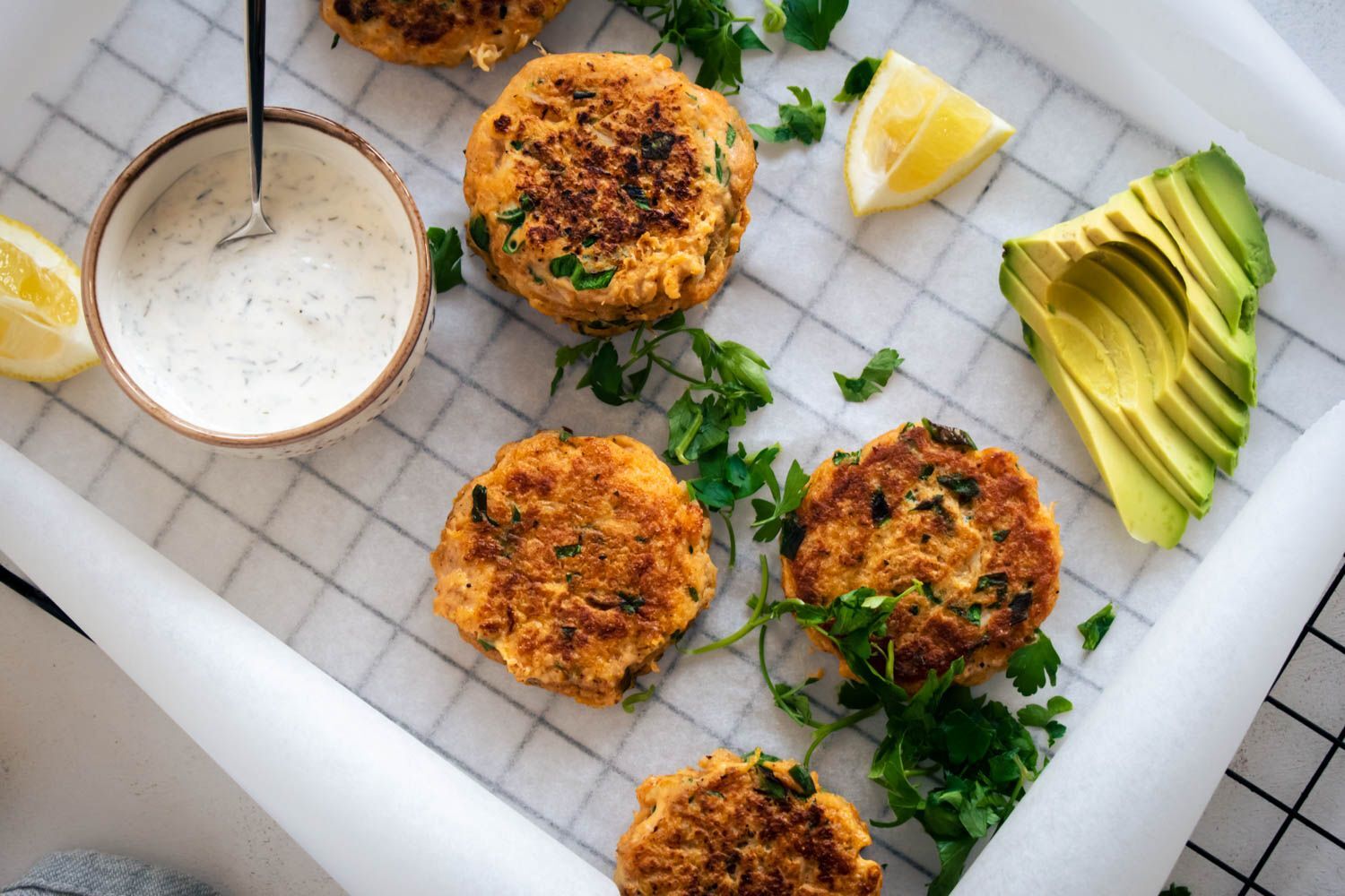Fish cakes made with cod and herbs baked until crispy on a baking sheet with lemon and dipping sauce.