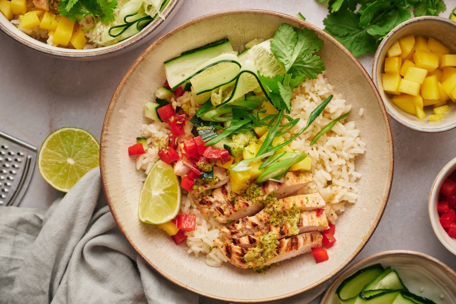 Grilled chicken bowls with citrus grilled chicken breast, rice, mango, red bell pepper, and cucumber in a bowl with cilantro.