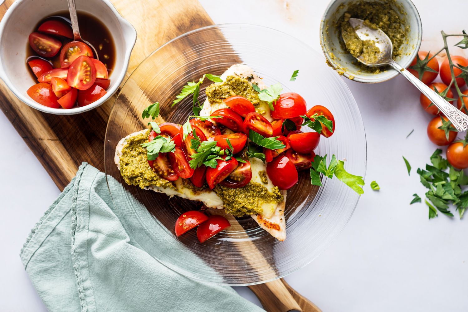 Grilled chicken margherita with cherry tomatoes, melted mozzarella cheese, and pesto on a plate.