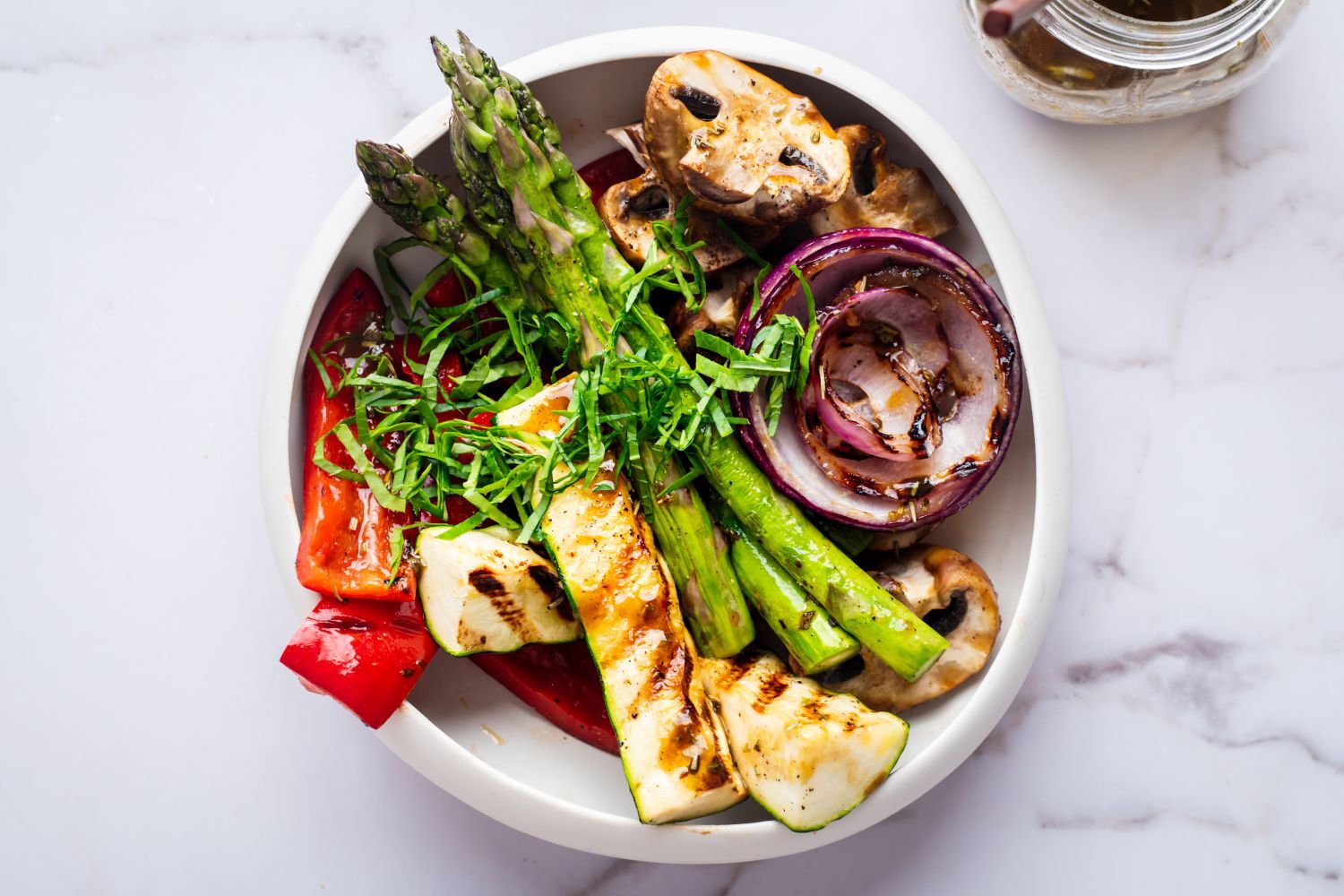 Grilled marinated vegetables with balsamic marinade in a white bowl.