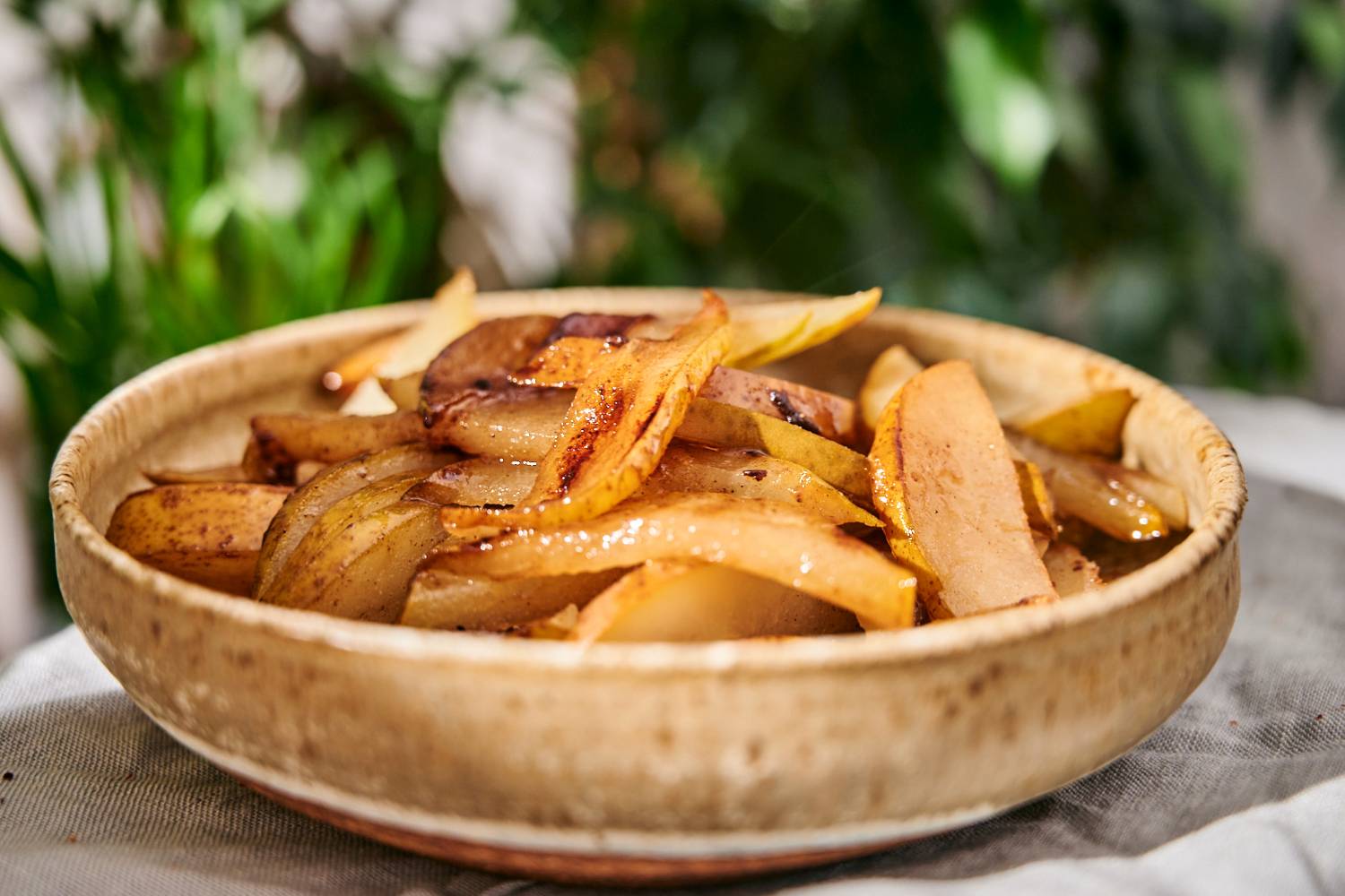 Grilled pears cut into slices with caramelized edges in a white bowl.