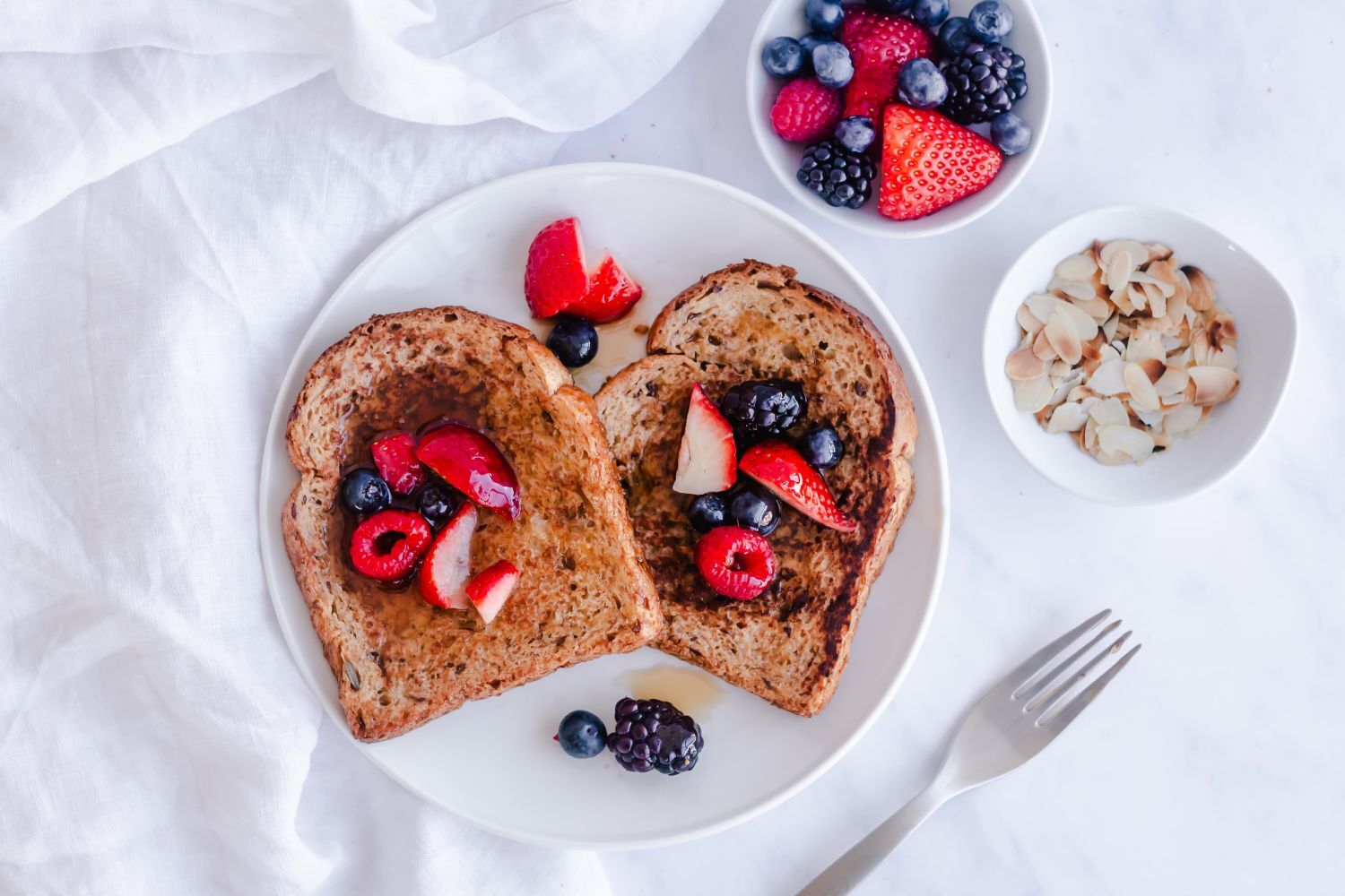 Healthy French toast made with whole wheat bread and topped with fresh berries and almonds.