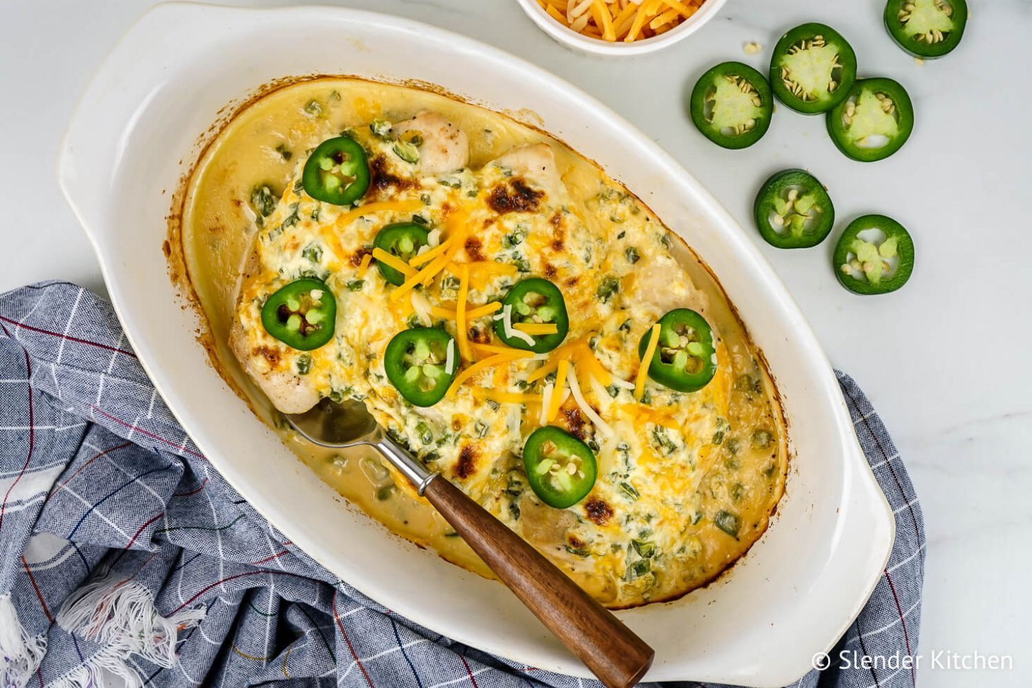 Jalapeno Popper Chicken with cream cheese, cheddar cheese, jalapeno, and chicken breast in a casserole dish.