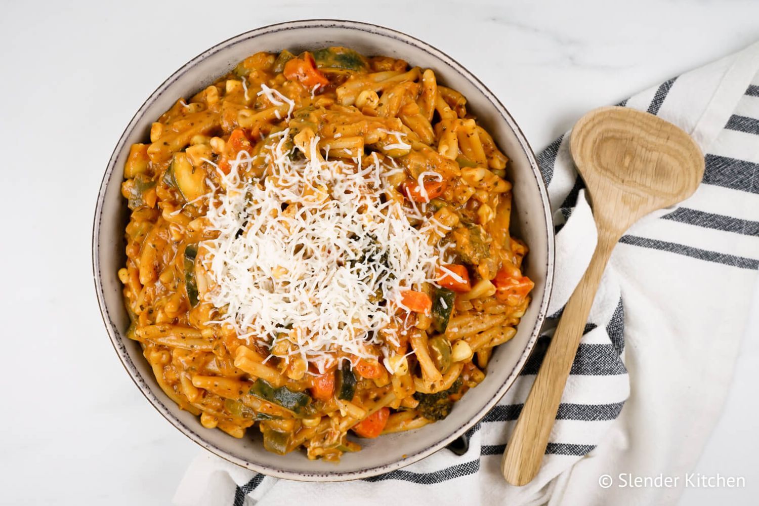 One pot creamy vegetable pasta with tomato sauce in bowl with mozzarella cheese.