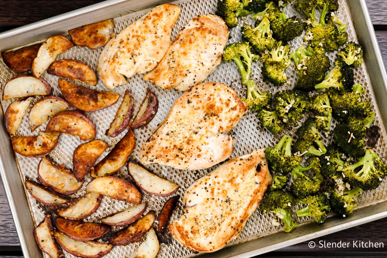 Roasted chicken with potatoes and broccoli on a sheet pan.