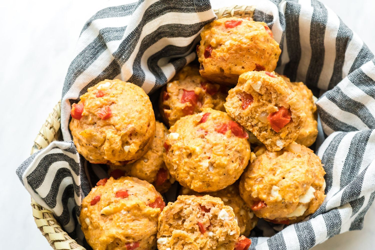 Savory feta cheese muffins with red peppers and feta crumbles served in a basket.
