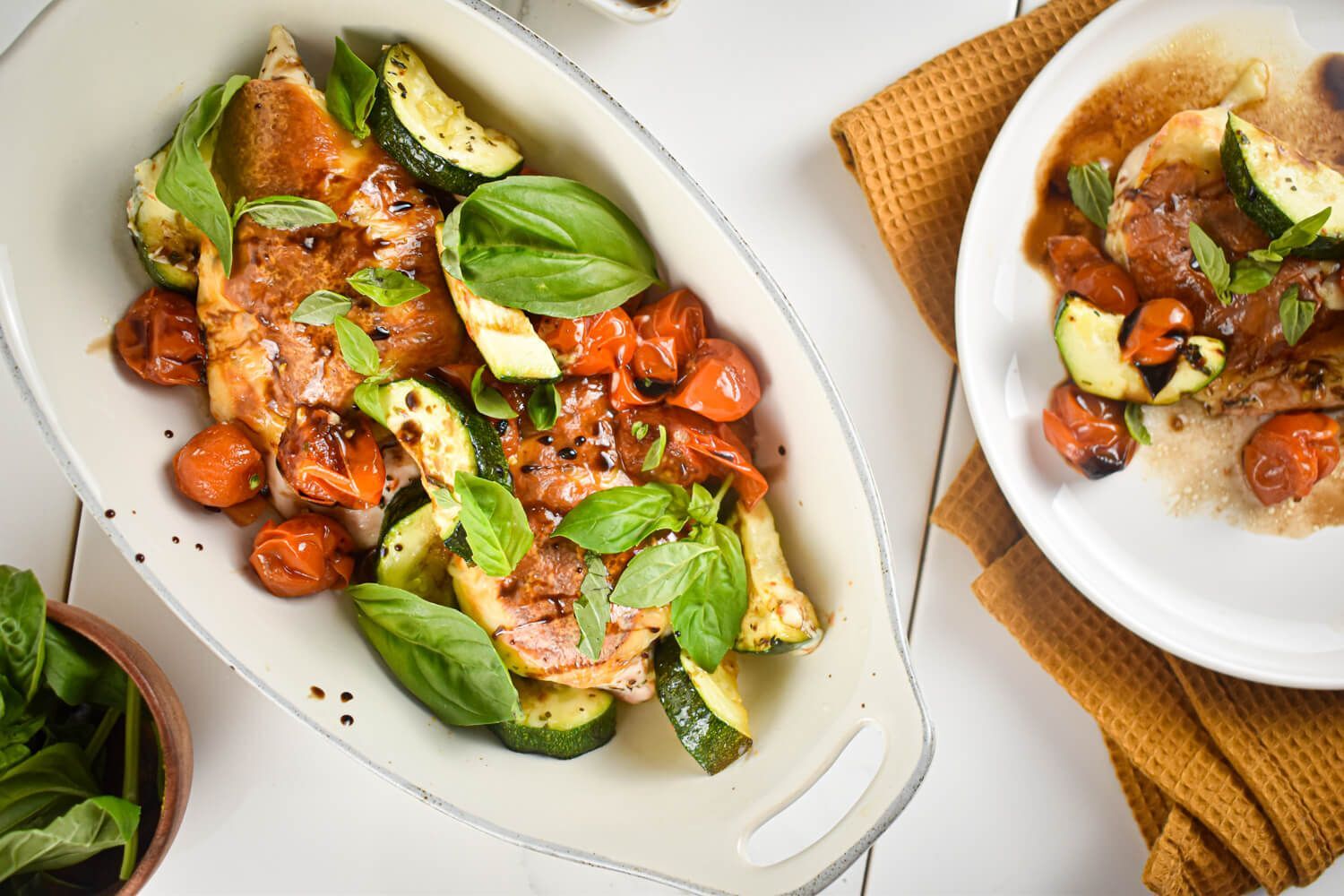 Caprese chicken with zucchini, tomatoes, basil, and cheese in a casserole dish.
