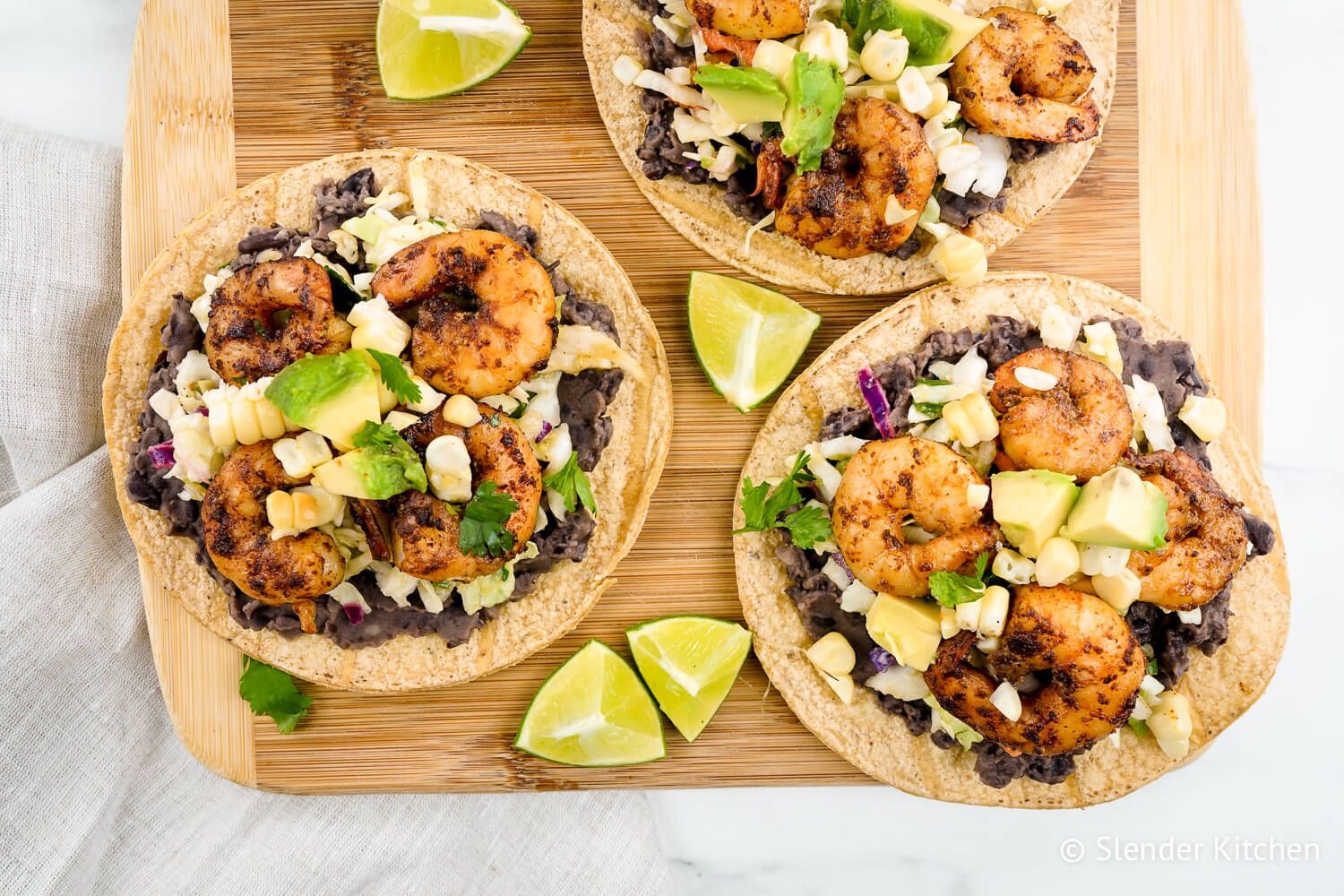 Shrimp tostadas with black beans, cabbage, spiced shrimp, avocado, and corn on baked tortillas.