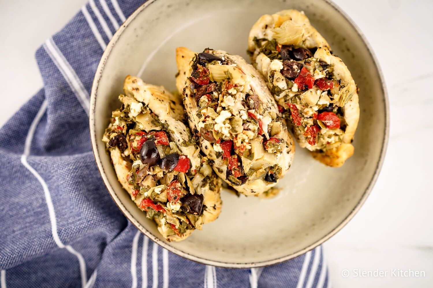 Skow Cooker Greek Chicken Breats stuffed with feta, olives, spinach, red peppers, and artichoke hearts.