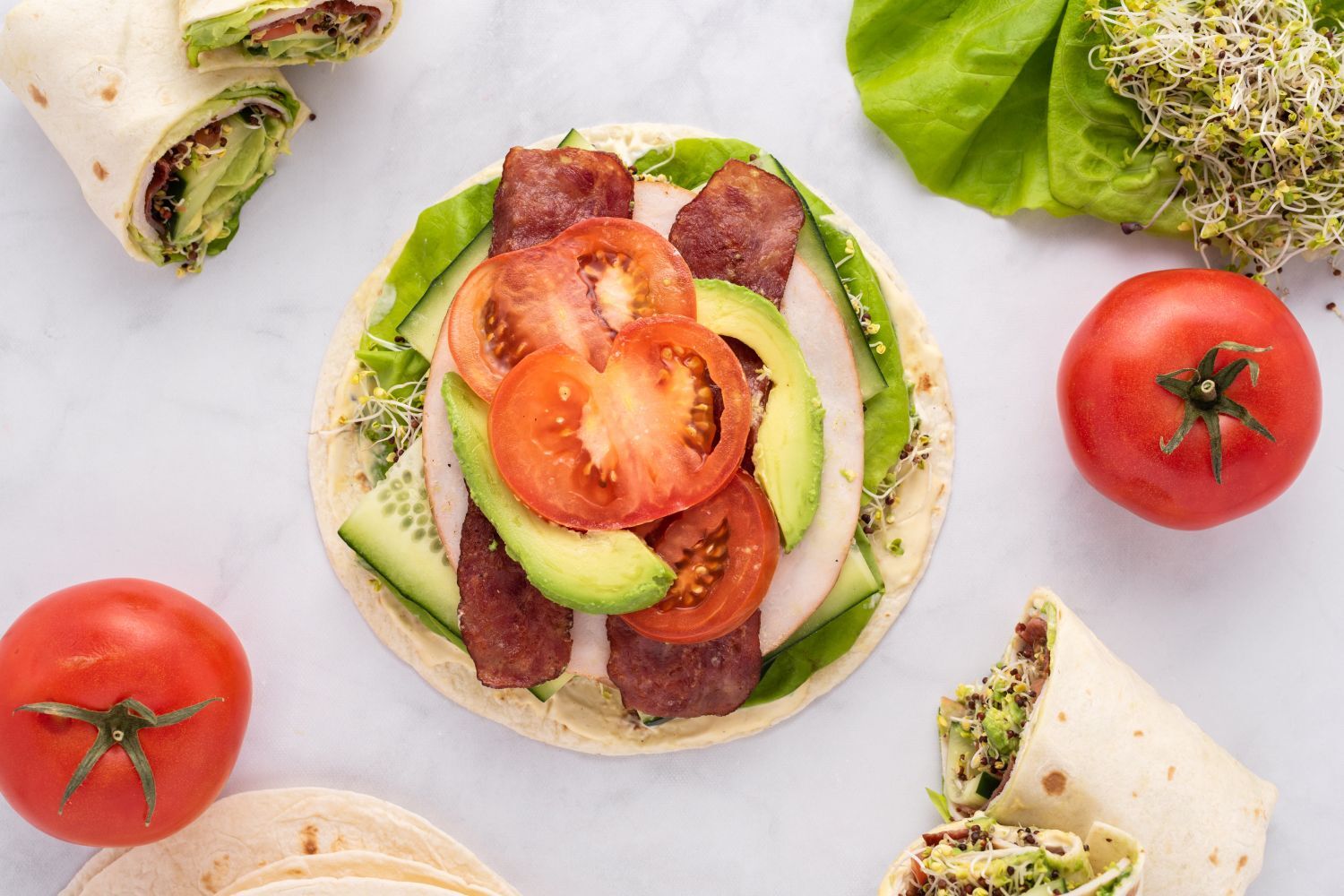 Turkey BLT wraps with deli turkey, cooked bacon, lettuce, tomato, and sprouts on a wrap.