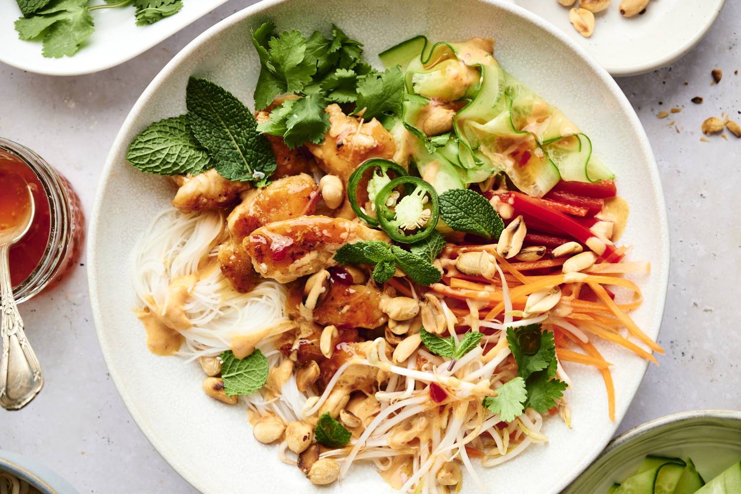 Vermicelli noodles bowls with sweet chili chicken, noodles, carrots, bean sprouts, cucumbers, carrots, peanuts, and fresh herbs.