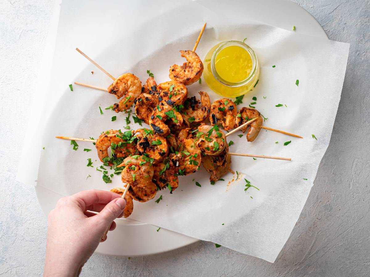 Grilled shrimp on wooden skewers with spices, lemon juice, and melted butter.