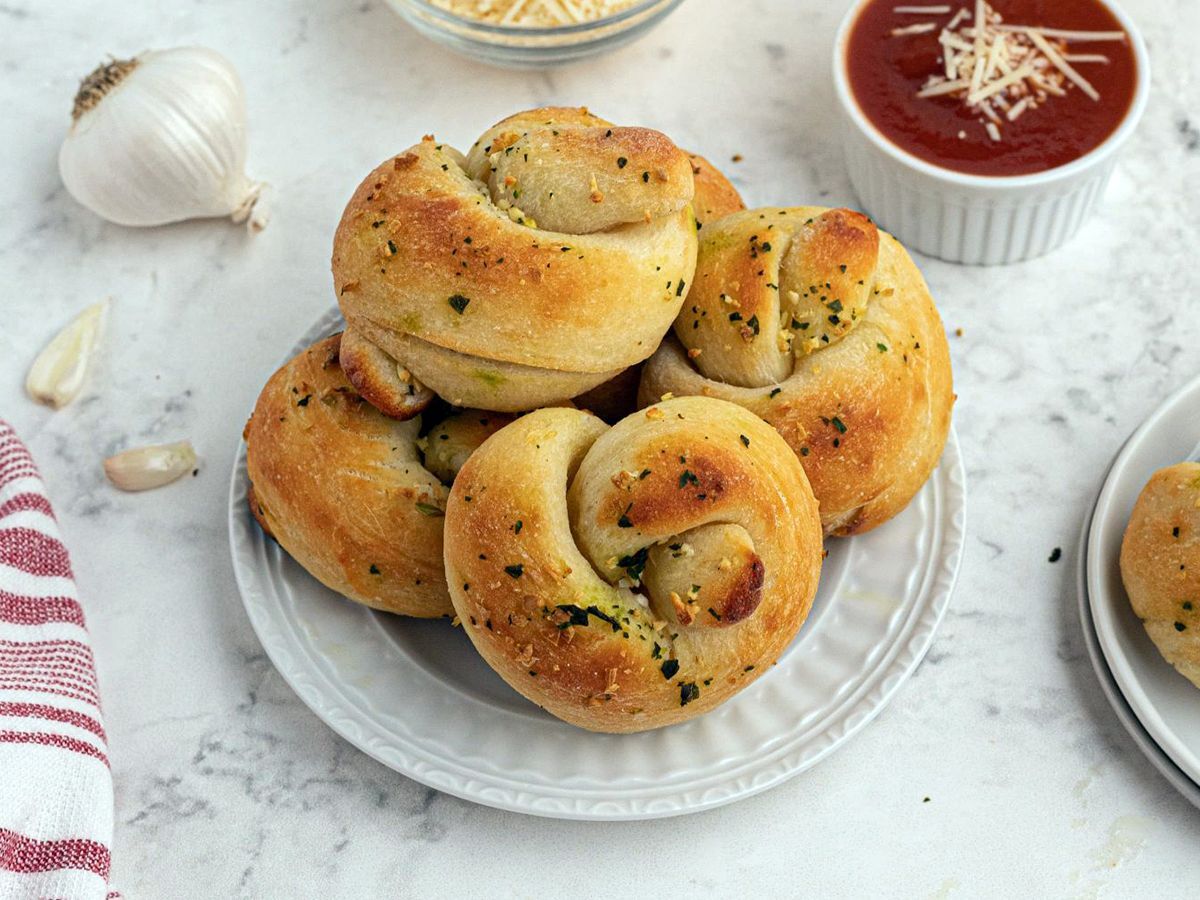 Homemade Garlic Knots Decorated with Garlic Cloves and Marinara Sauce