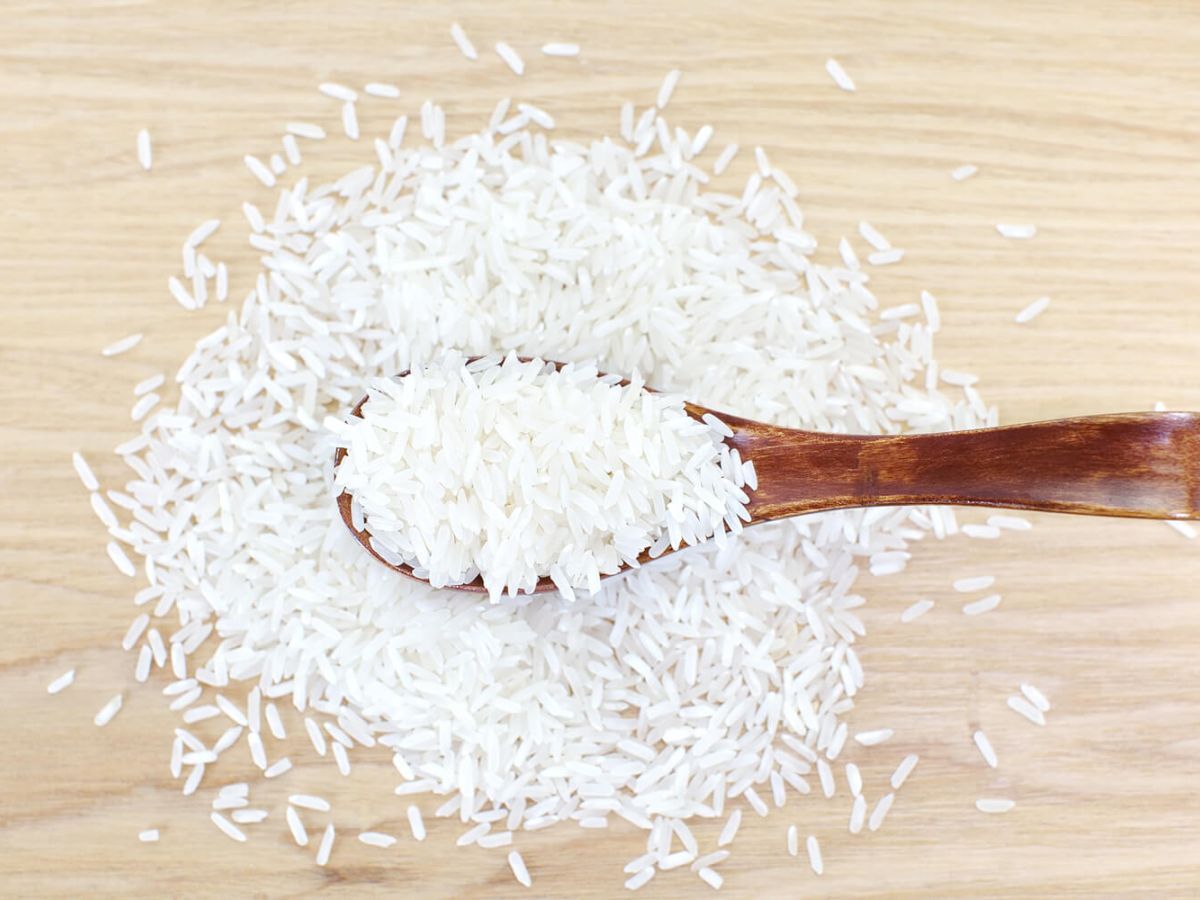 White rice on a wooden surface and a wood spoon