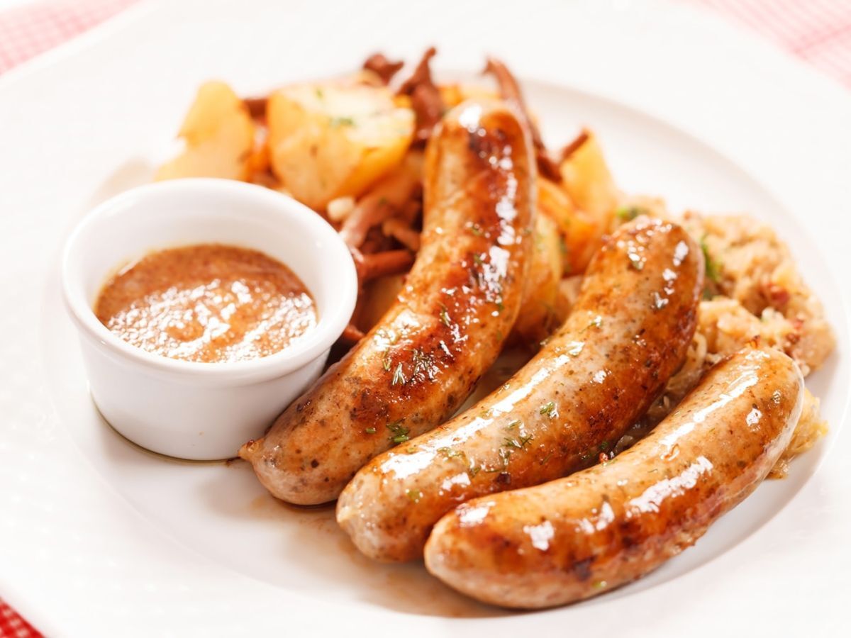 Cooked sausages with dipping sauce on a white plate