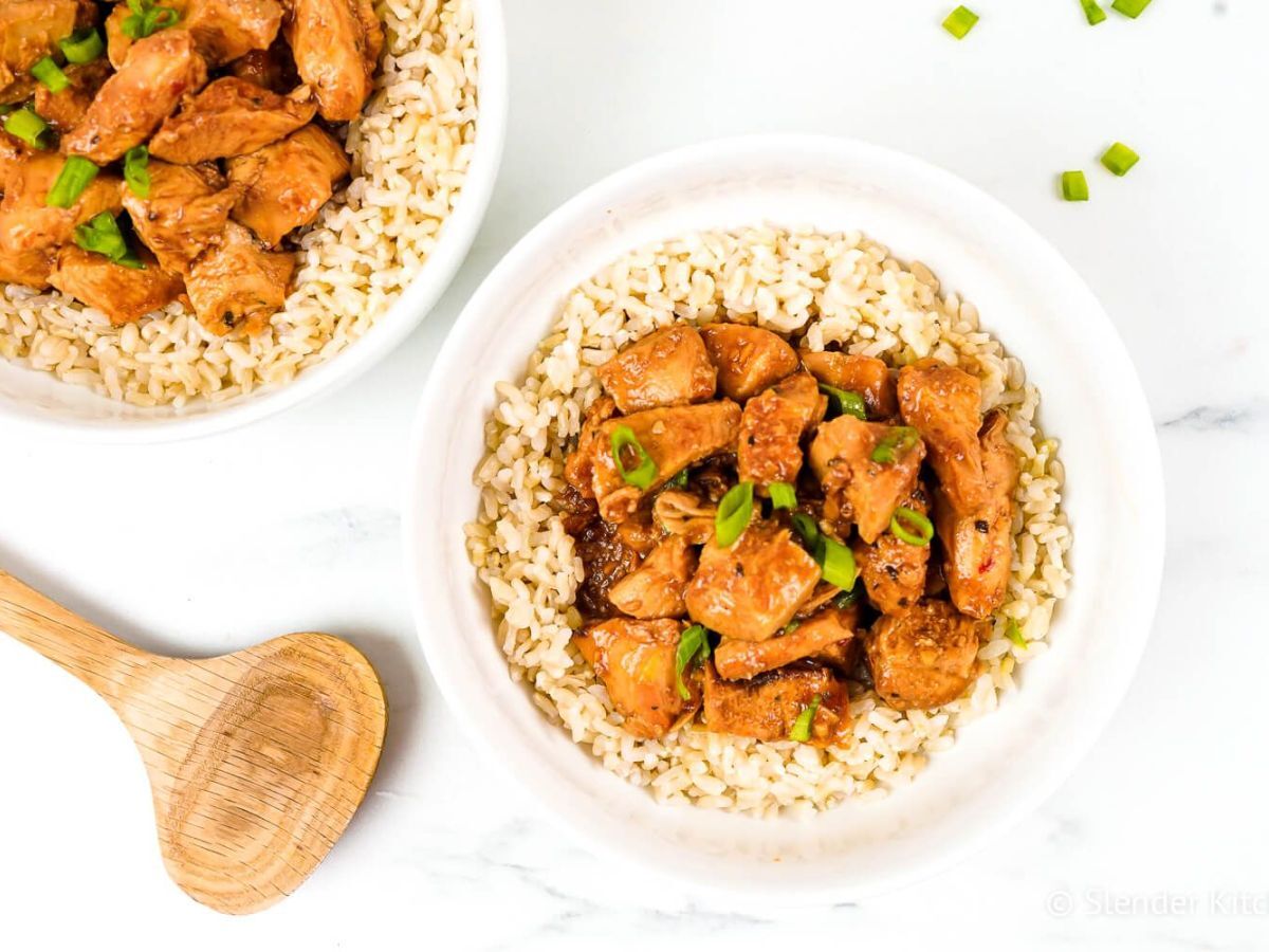 Slow cooker honey garlic chicken with green onions over a bed of brown rice.