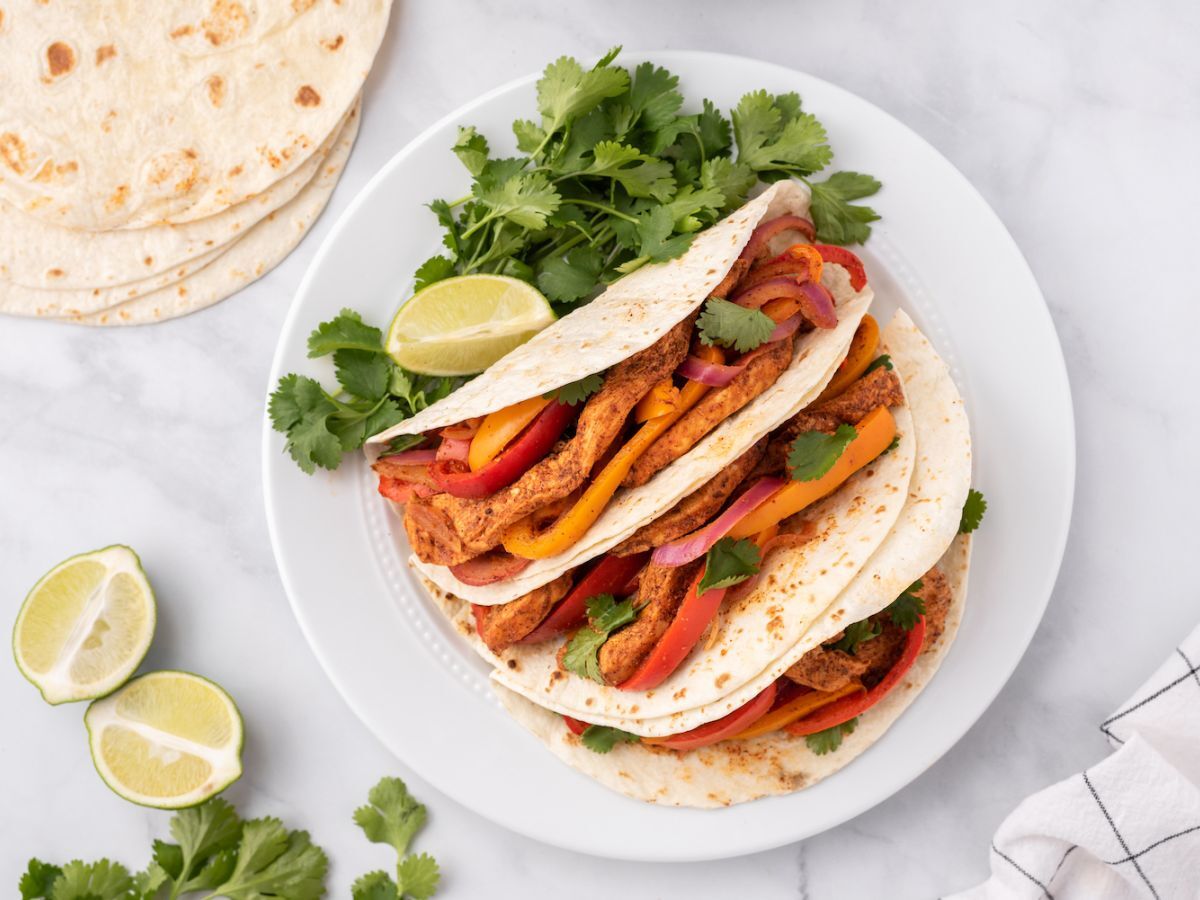 Chicken fajitas with peppers, onions, and cilantro in flour tortillas.