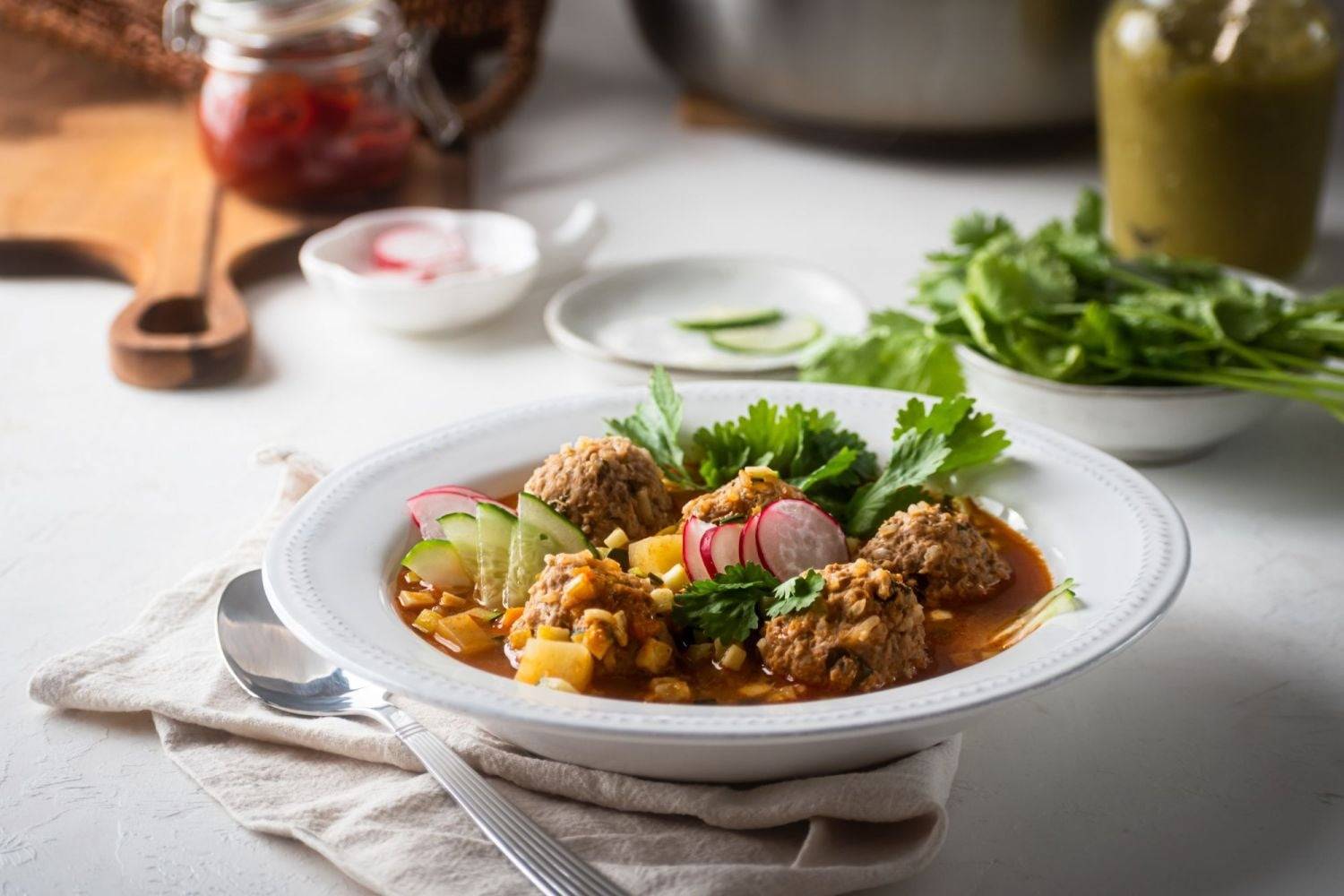Mexican meatball soup, made with ground beef and rice, served in a bowl with cilantro and radish.