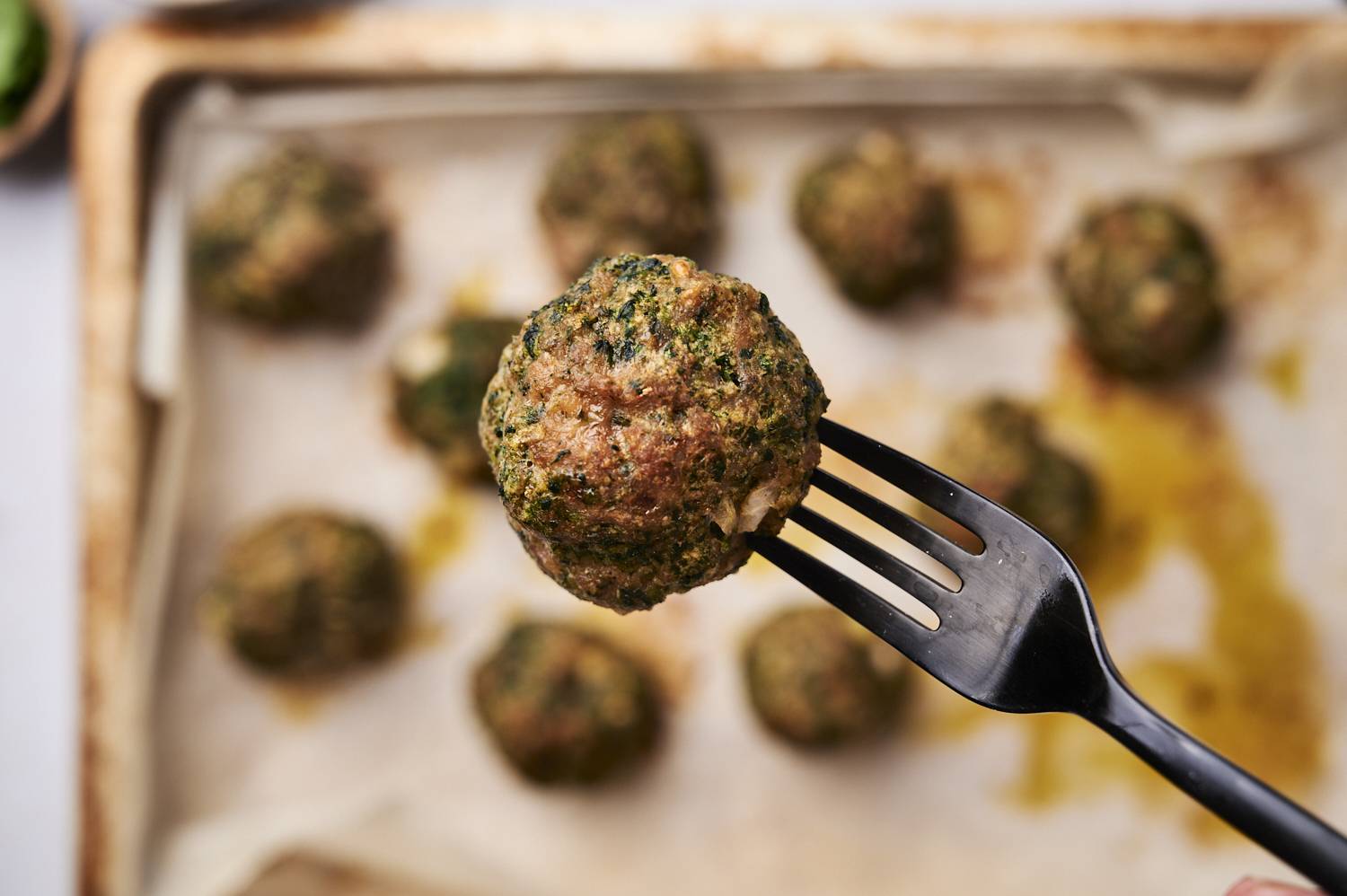 Baked spinach meatballs on a fork.