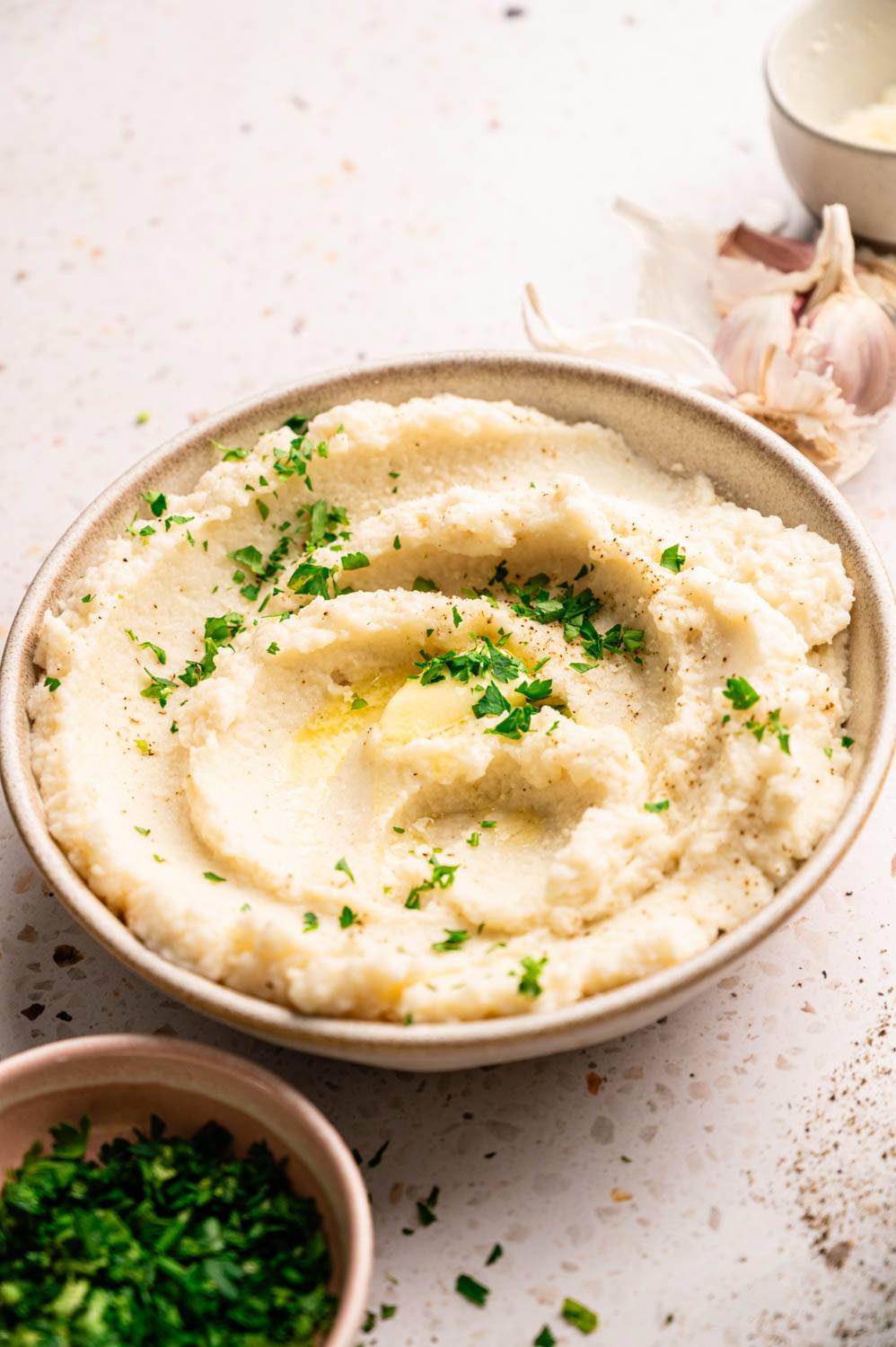 Creamy mashed potatoes in a bowl, garnished with fresh parsley and drizzled with melted butter