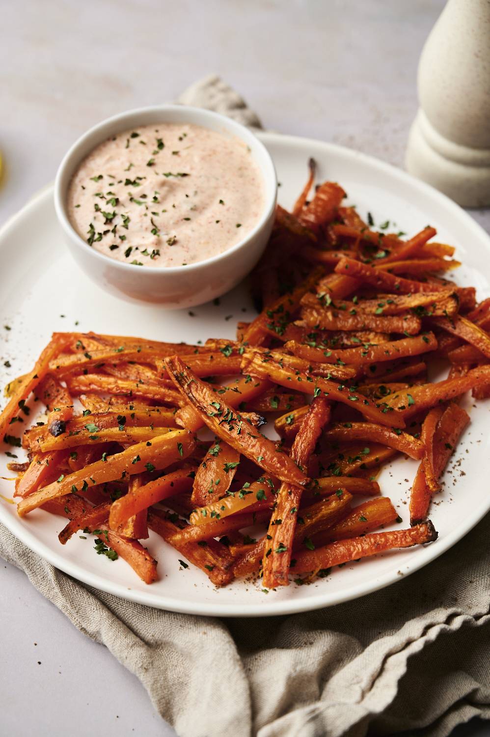 Vertical closeup of a bowl of roasted carrot fries.