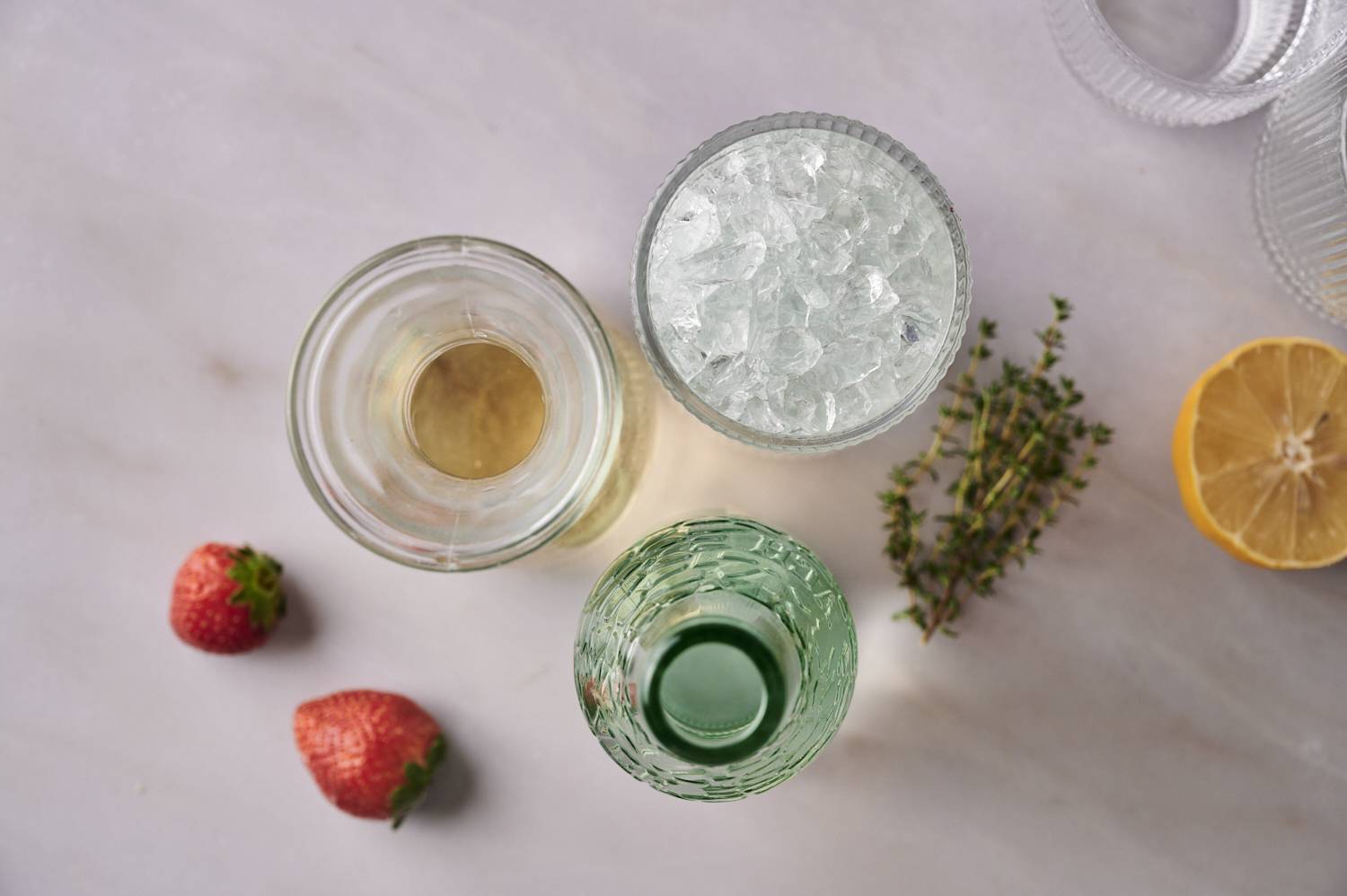 Top-down carafe, two glasses, strawberry, lemon and a thyme.
