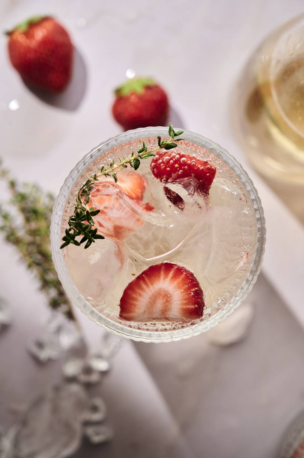 Top-down white wine spray with strawberry and thyme sprigs.