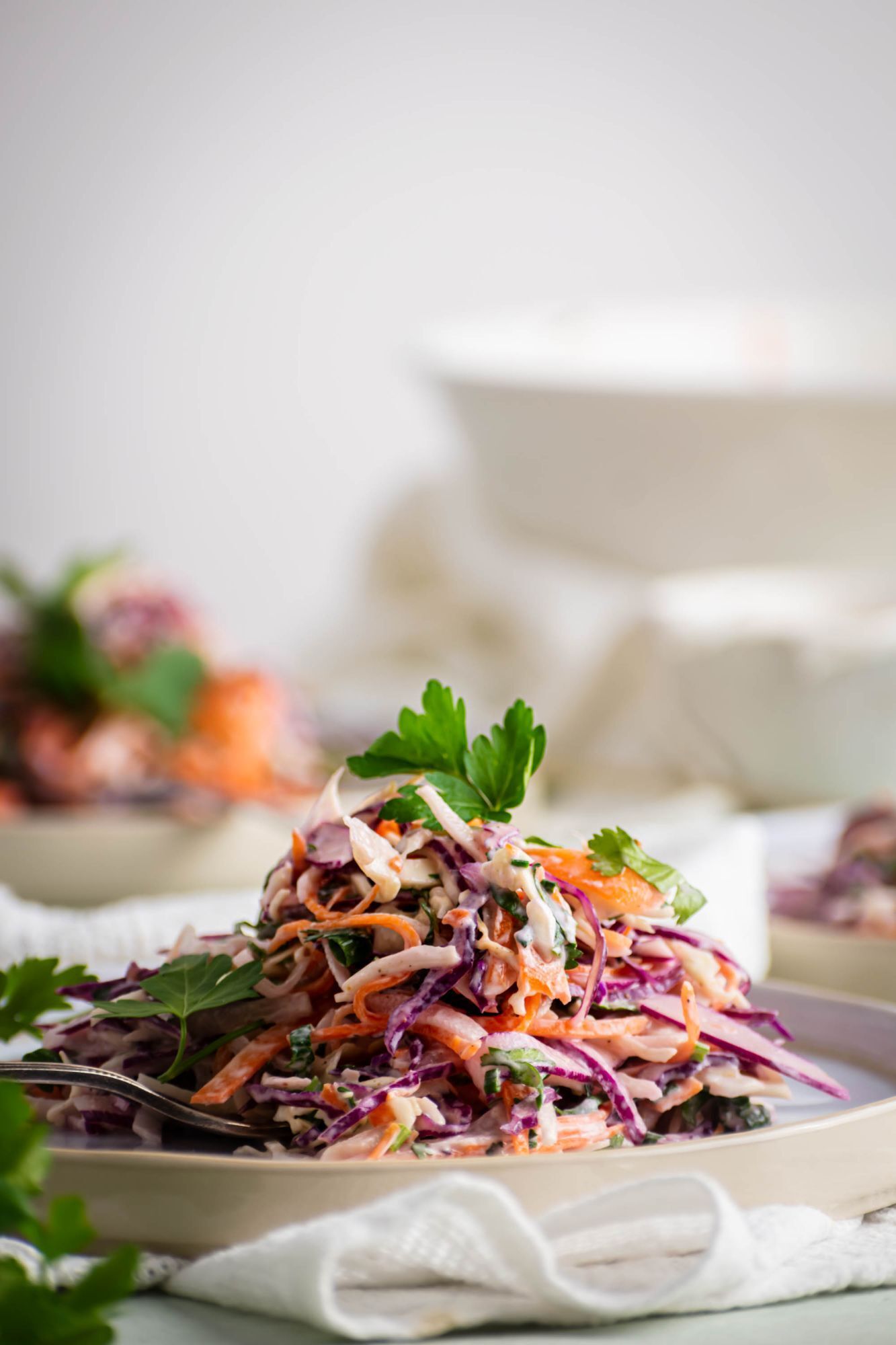 Greek yogurt coleslaw with chopped carrots, cabbage and herbs served on a plate.