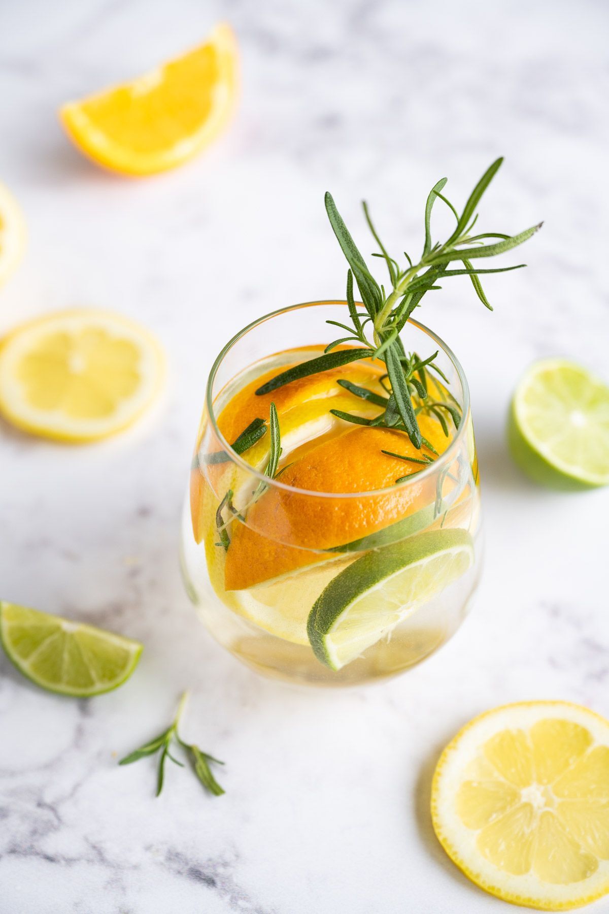 Lemon detox water in a glass, lemon slices, orange slices and lime slices.